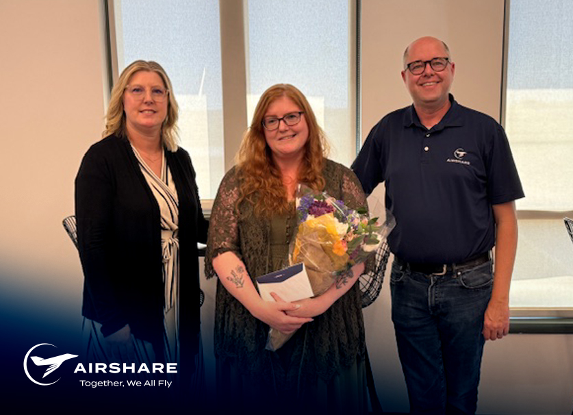 Airshare Employee accepting the Employee of the Month award while holding flowers and smiling with excitement next to her boss and the CFO.