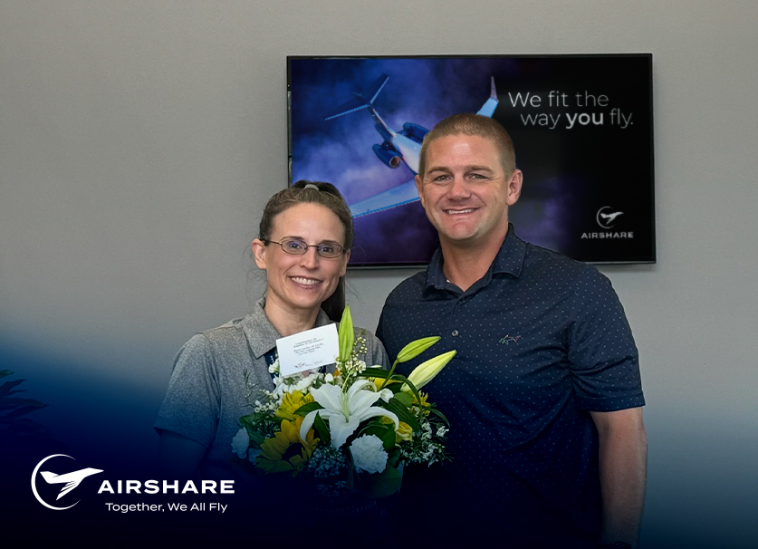 Airshare Employee accepting the Employee of the Month award while holding flowers and smiling with excitement next to her boss.