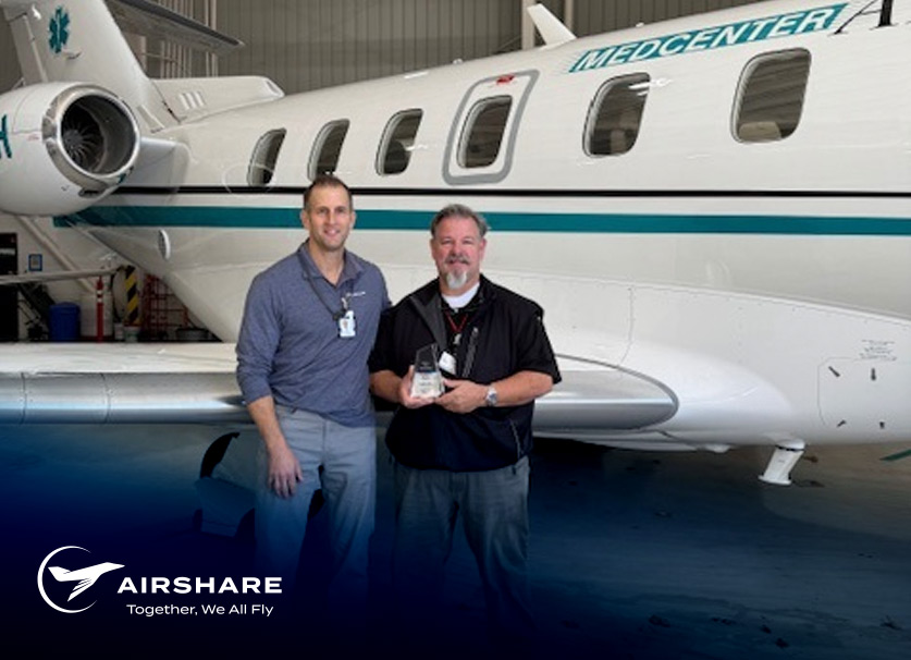 Airshare Employee accepting the Employee of the Month award while holding the EoM crystal and smiling next to his boss.