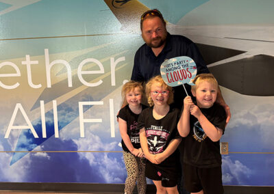 Family that participated in Bring Your Kid To Work Day pictured in front of wall.