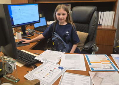 Kid that participated in Bring Your Kid To Work Day seated at a desk in Airshare office.