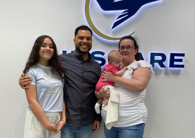 An Airshare employee with family that participated in Bring Your Kid To Work Day in front of Teterboro Airshare sign.
