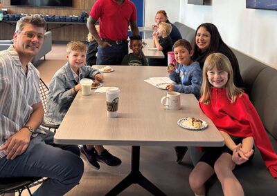 Parents and kids that participated in Bring Your Kid To Work Day seated in the Galley having donuts and coffee for breakfast.