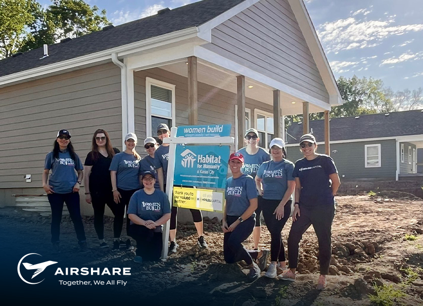 Hero-Img-Volunteers-AS-Kompass Group photo of volunteers from Airshare, Dynamic Logistix, Kompass Kaptial, and Moonshot Solutions outside if house they're volunteering with Habitat KC to help build.