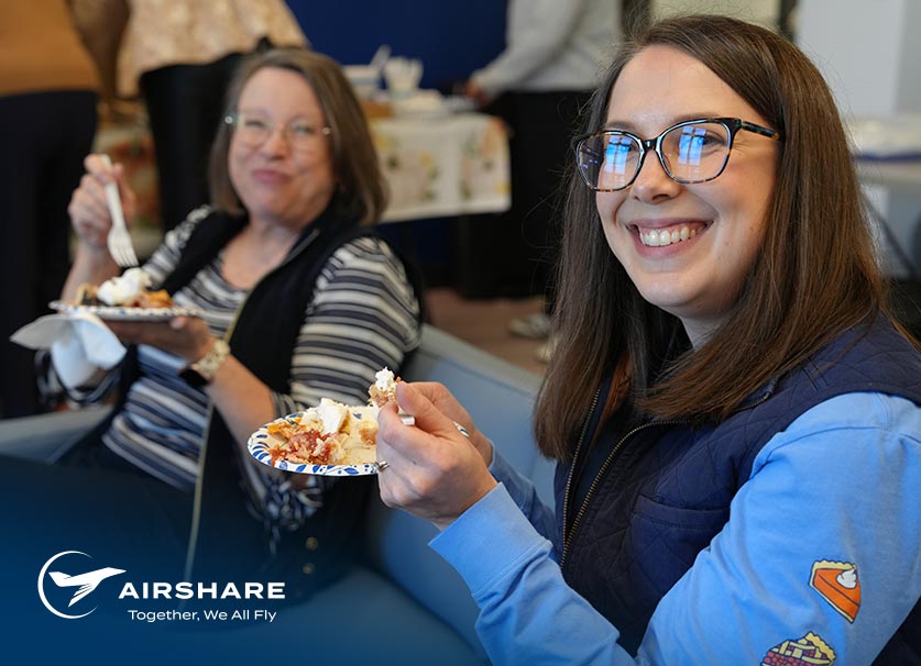 Airshare employees seated and smiling at camera while enjoying pie.