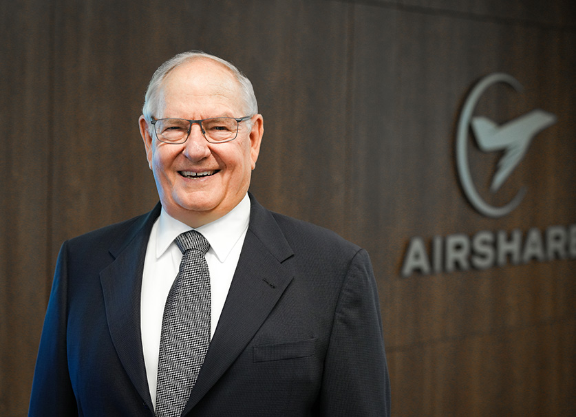 Airshare founder, Bob Taylor, posed in front of wooden wall with Airshare signage.