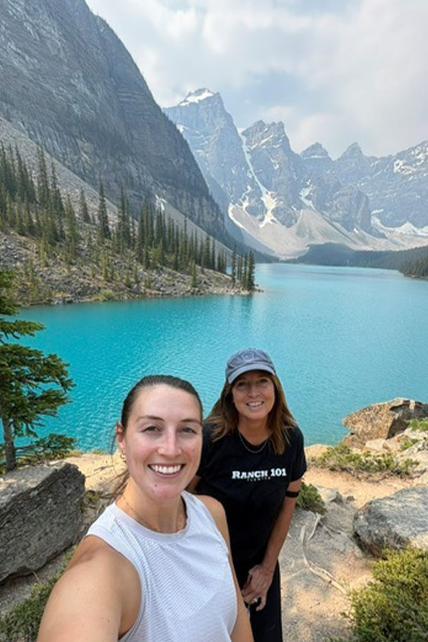 Two Airshare pilots posing in front of the turquoise waters and mountain scenery at Moraine Lake in Banff National Park.